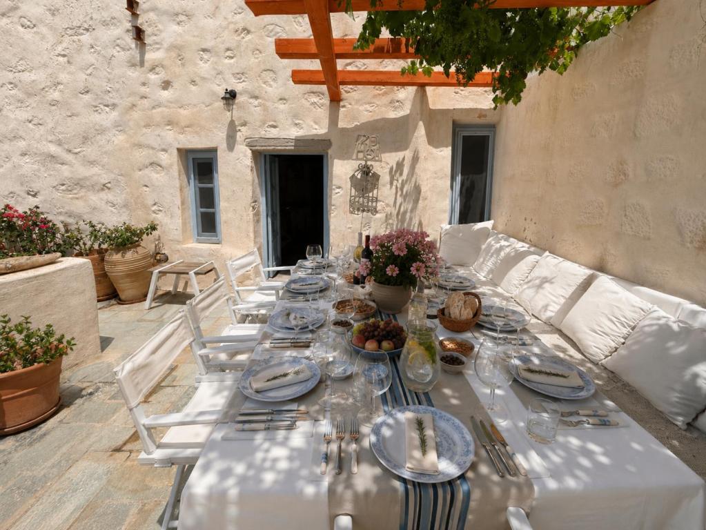 a long table with plates and glasses on a patio at Chora Heritage Residence by Belle-Stay in Patmos