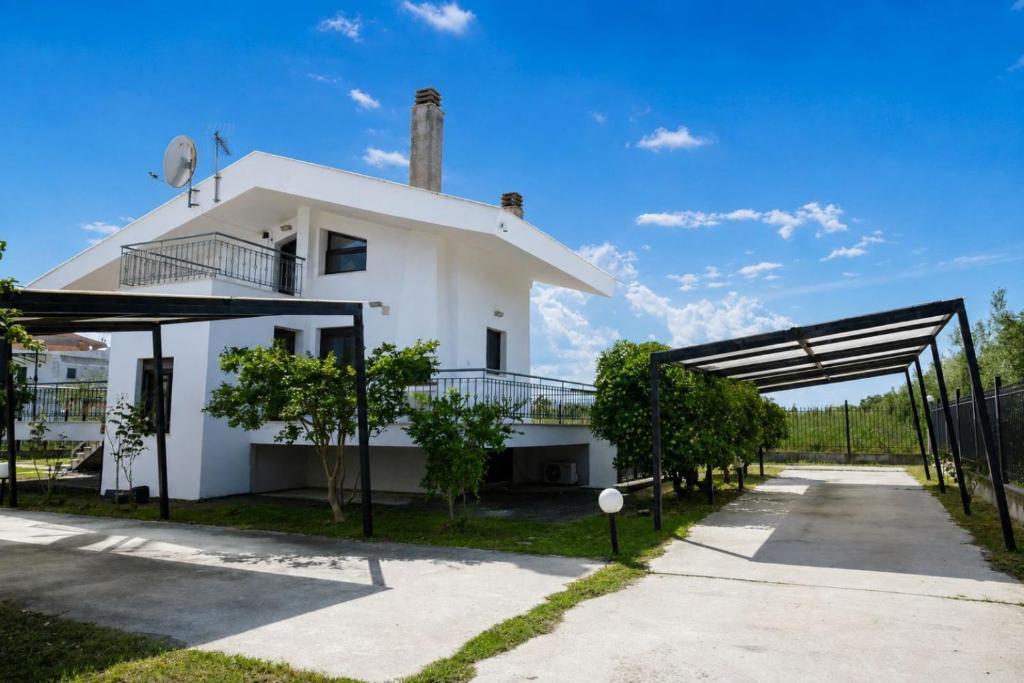 a white house with a gate in front of it at Olive Garden Vila in Karianí