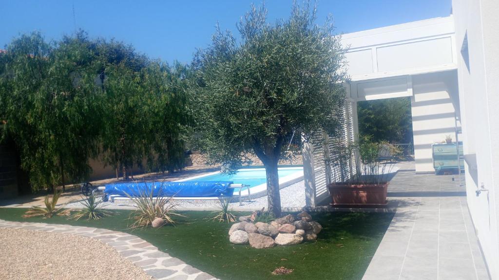 a swimming pool with a tree and rocks in the water at Chambre indépendante climatisée in Laroque-des-Albères