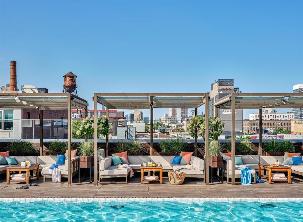a pool with couches and tables next to a building at The William Vale in Brooklyn