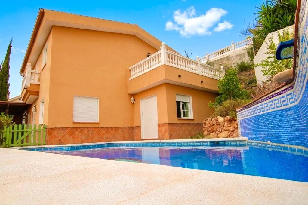 a villa with a swimming pool in front of a house at Bello horizonte in Coín