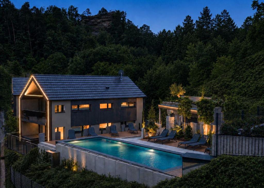 a home with a swimming pool in front of a house at Felsenland BERGVILLEN in Dahn