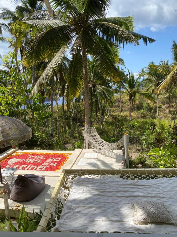 a resort with a hammock and a palm tree at Exotic private glamping in Nusa Penida