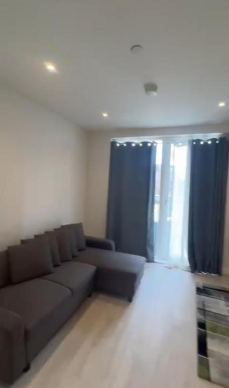 a living room with a couch and blue curtains at Harrow Nest - 1Bedroom in Hatch End