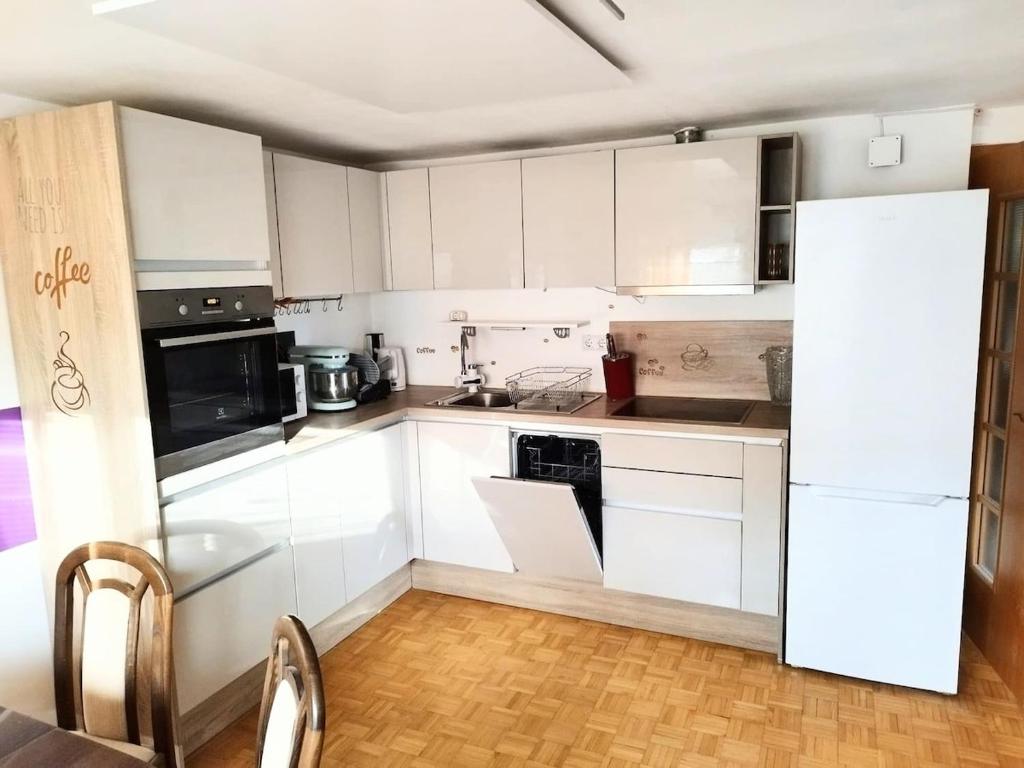 a kitchen with white cabinets and a white refrigerator at Signature events in Malečnik