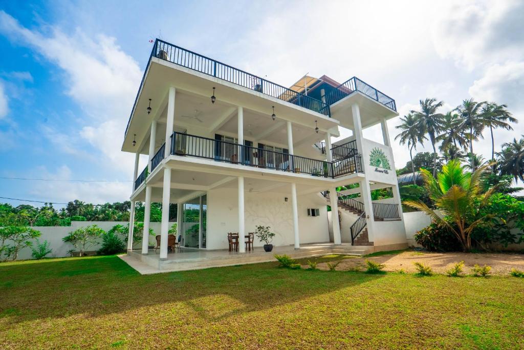 a white house with a balcony and a yard at Monara Villa in Dharga Town