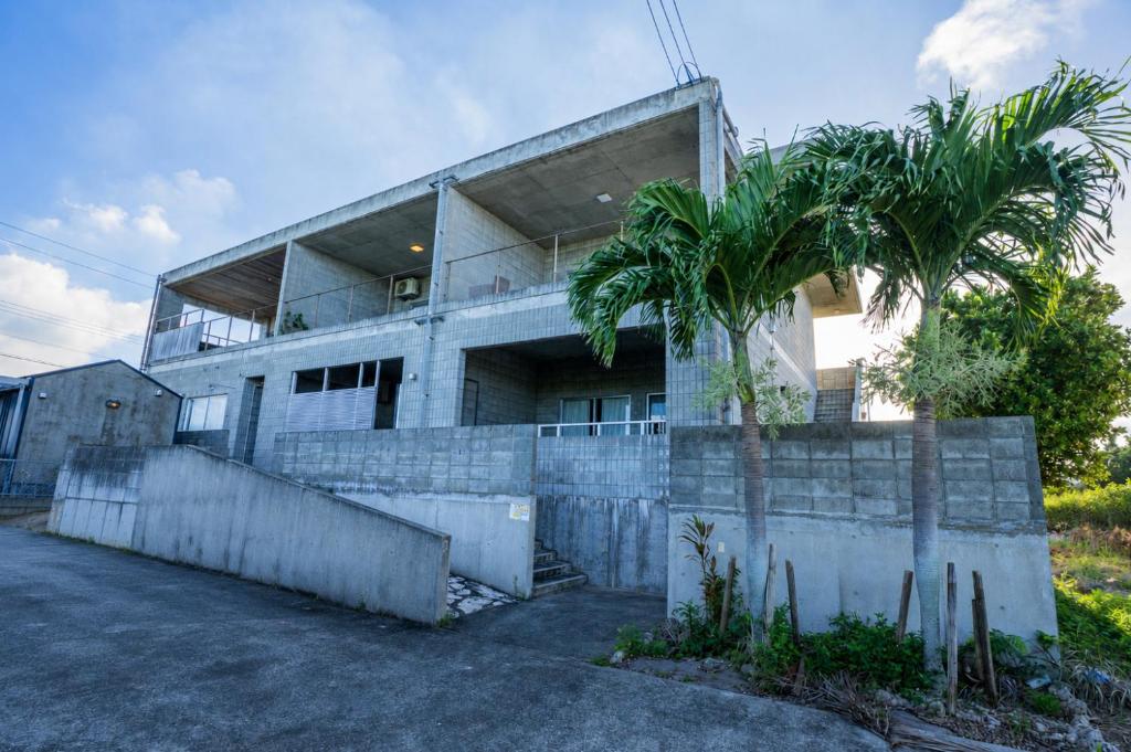 ein Gebäude mit einer Palme davor in der Unterkunft vividテラス101 in Miyako-jima