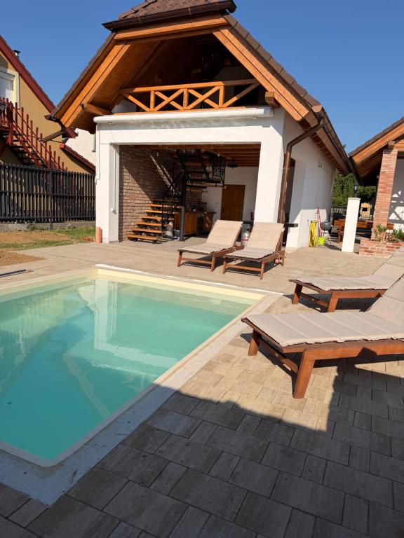 a swimming pool with two lounge chairs and a house at Mariska in Balatonkeresztúr