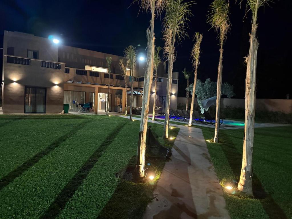 a lawn with palm trees in front of a building at VILLA Noor Atlas in Aghmat