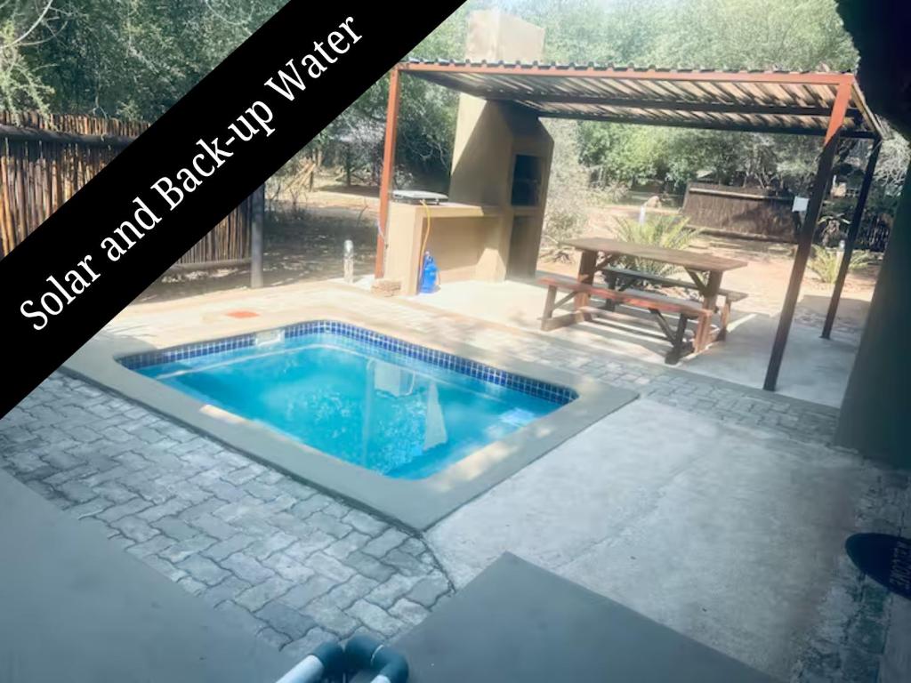 a swimming pool in a backyard with a picnic table at Athule Inn Marloth - Units in Marloth Park