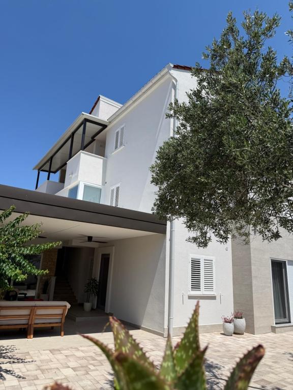 a white building with a tree in front of it at Apartmani Pernjak in Mandre