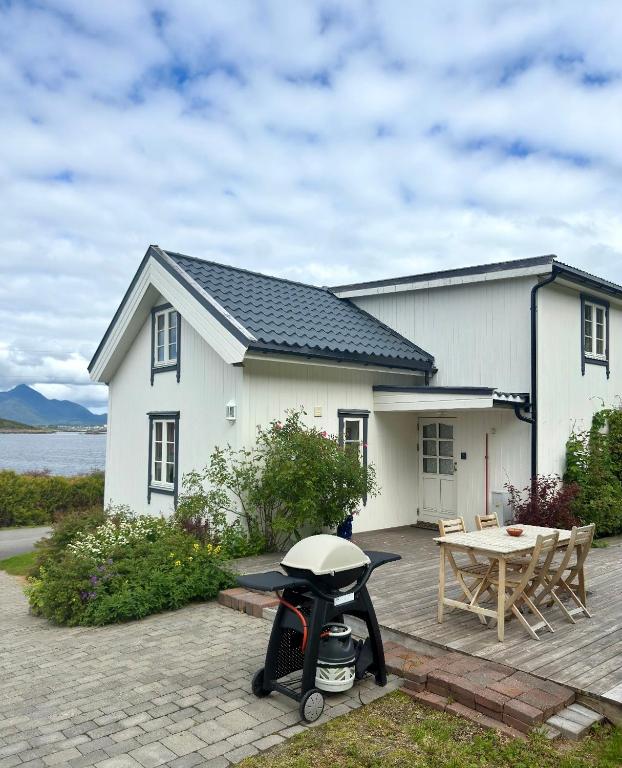 a white house with a table and a bike in front of it at Heritage House in Lofoten with Modern Comfort & Scenic Views in Jerstad