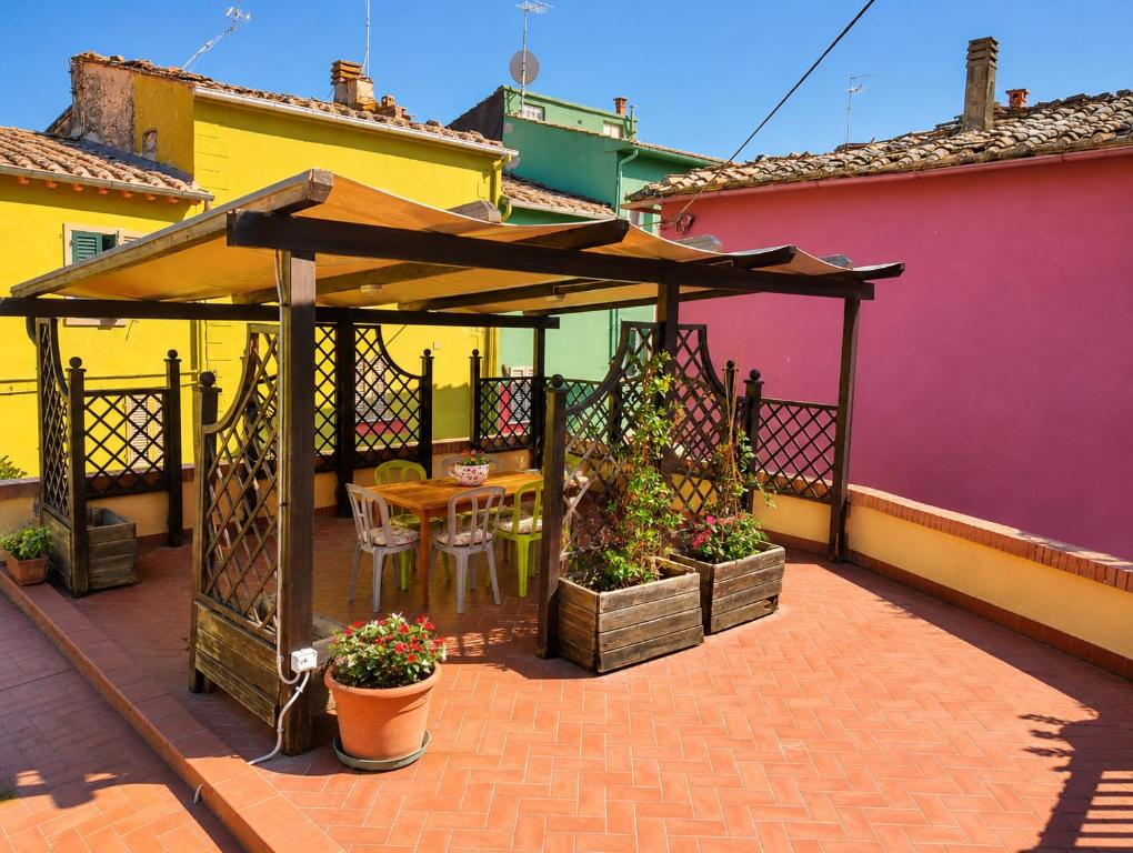 a patio with a gazebo with a table and flowers at La terrazza di Isma in Ghizzano