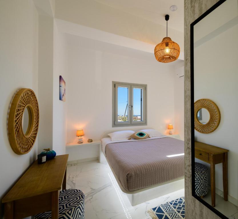 a white bedroom with a bed and a mirror at Santana Apartments in Perivolos