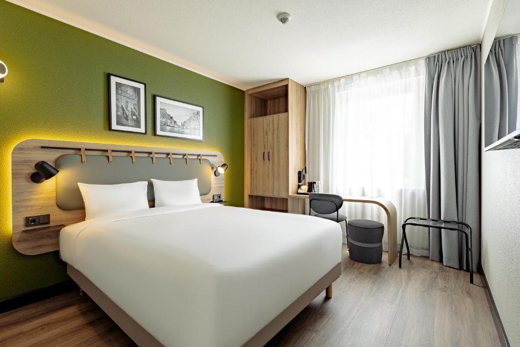 ein Schlafzimmer mit einem großen Bett und einer grünen Wand in der Unterkunft Campanile PRIME - Wroclaw Stare Miasto in Breslau