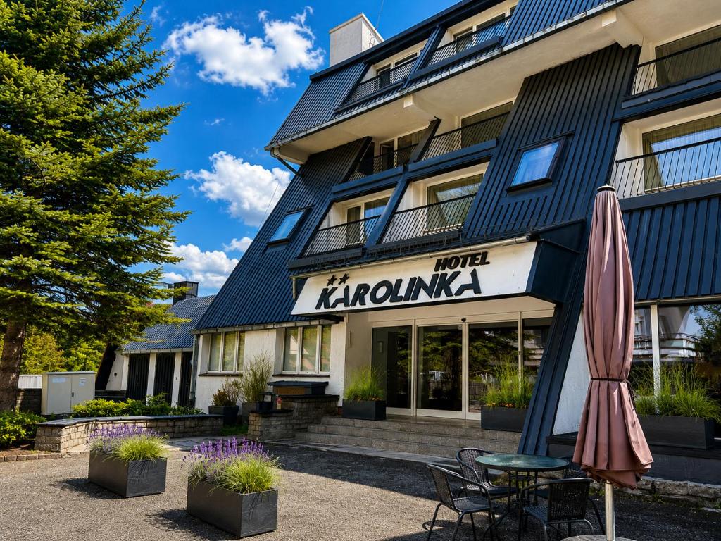 a hotel with a table and an umbrella in front of it at Hotel Karolinka in Karpacz