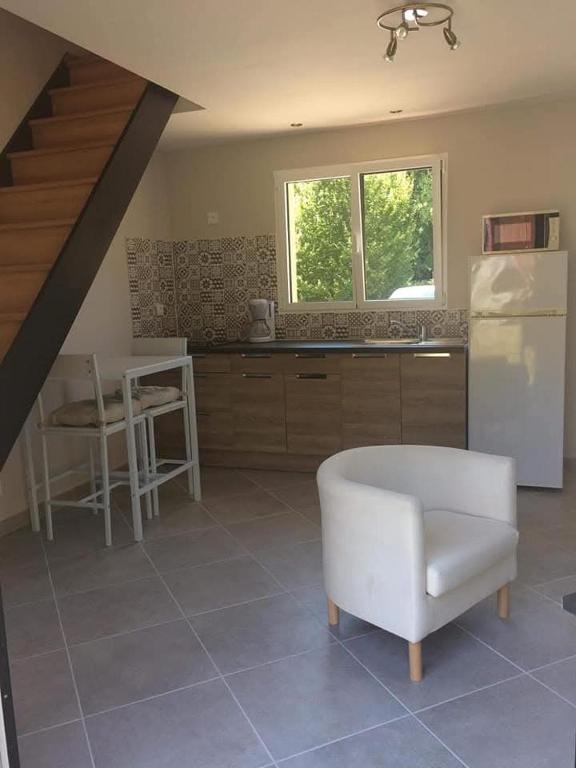 a kitchen with a white chair and a refrigerator at Studio a la campagne in Les Bordes