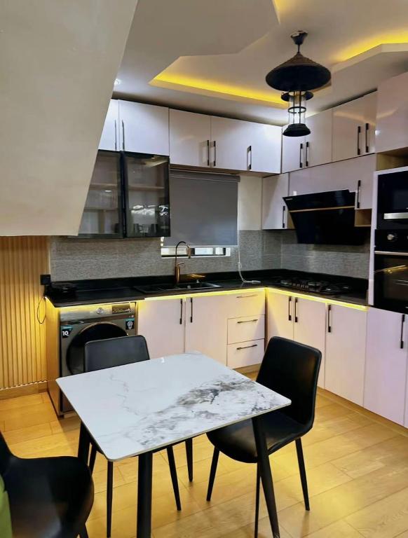 a kitchen with white cabinets and a table and chairs at North Unit in Asaba