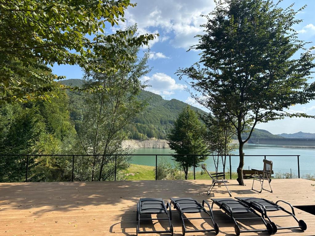 a group of chairs sitting in front of a lake at Paltinu Lake Villas in Teşila