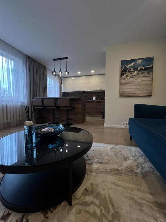 a living room with a table and a blue couch at Taikos apartments in Kupiškis