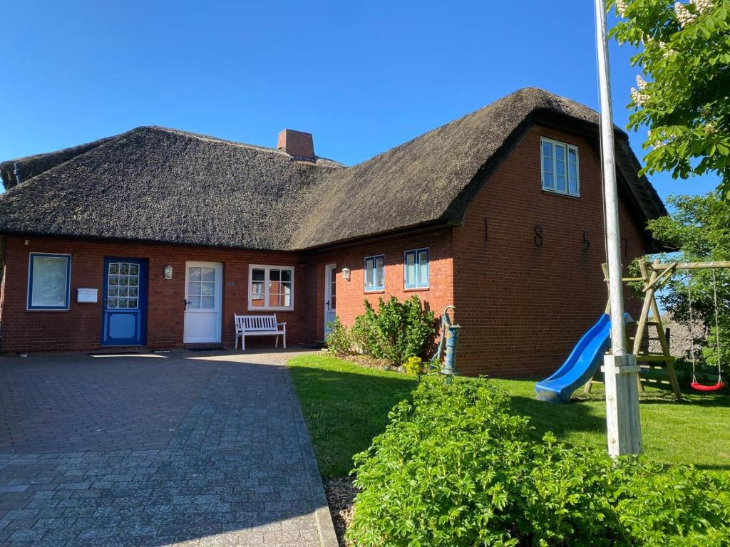 a brick house with a blue door and a playground at Ferienwohnung Wattwurm Ockholm in Ockholm