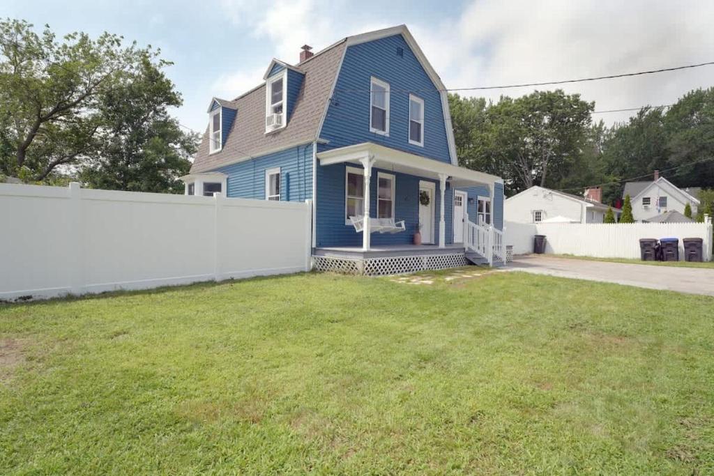 a blue house with a white fence in a yard at Beautiful Modern Beach House! in Old Orchard Beach