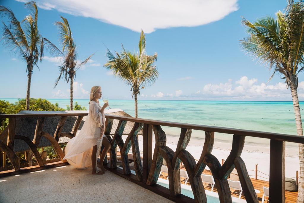 a woman standing on a balcony overlooking the beach at Casa Rodi Zanzibar in Jambiani