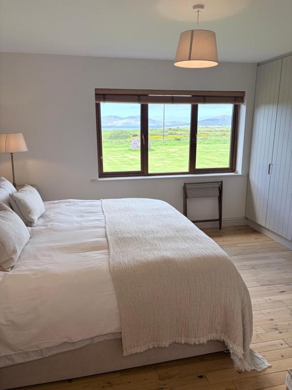 a bedroom with a large bed with a large window at Murreigh Beag Waterville in Waterville