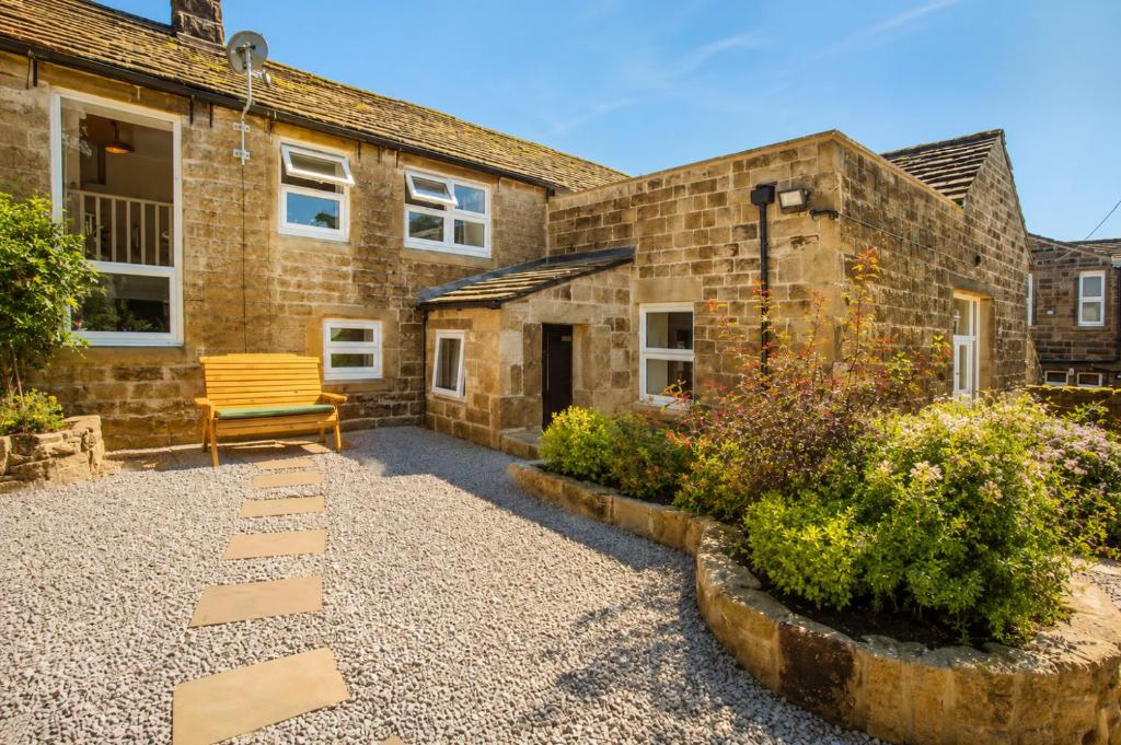 a stone house with a bench in front of it at The Bronte Moor Retreat - 3 Bed, Pet Friendly Cottage - Stunning Views - Hot Tub in Heptonstall
