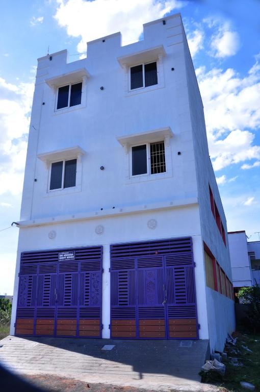 a white building with purple garage doors on it at Dharani Residency in Pondicherry