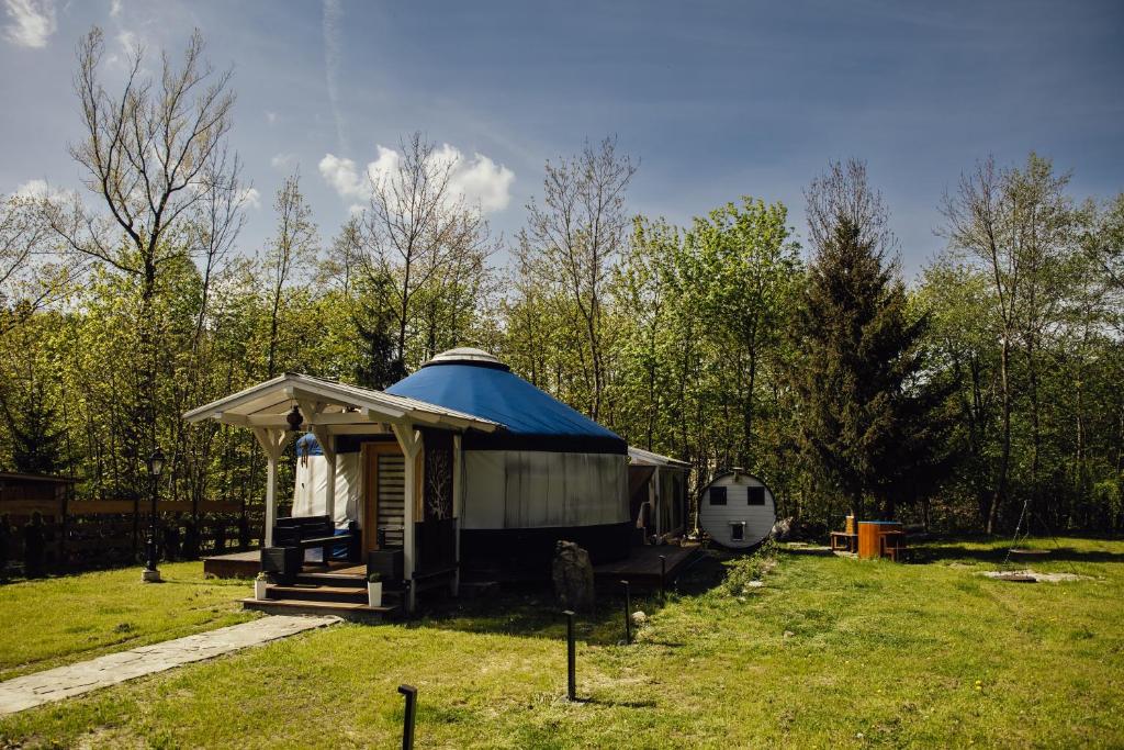 a yurt with a blue top sitting in a field at Slow Flow Glamp - sauna, basen i jacuzzi in Rzyki