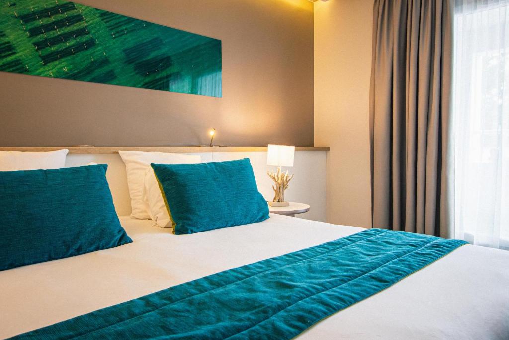 a bedroom with a large bed with blue pillows at Hôtel Le B d'Arcachon by Inwood Hotels in Arcachon