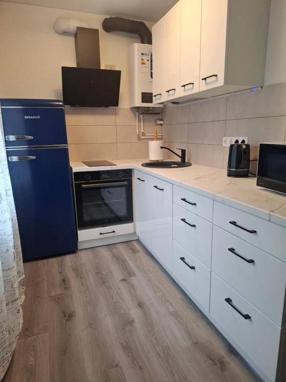 a kitchen with white cabinets and blue appliances at SV Apartment in Jõhvi