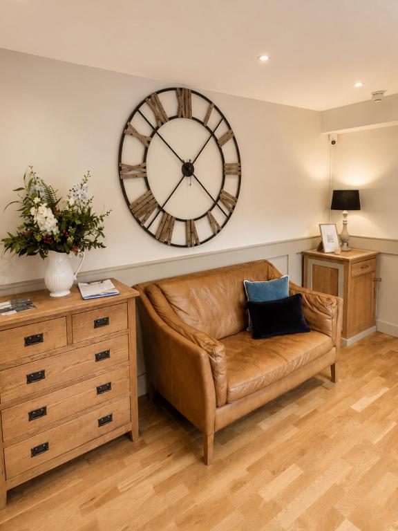 a brown leather couch with a large clock on the wall at The Lodge at Broadway in Broadway