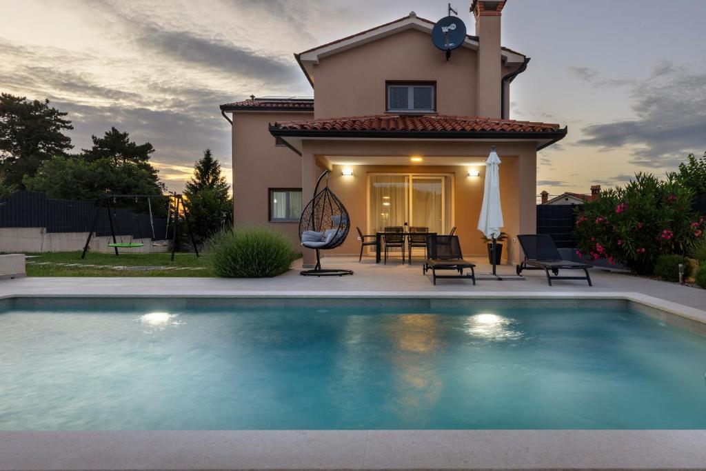 a villa with a swimming pool in front of a house at Villa Egli s bazenom in Kršan