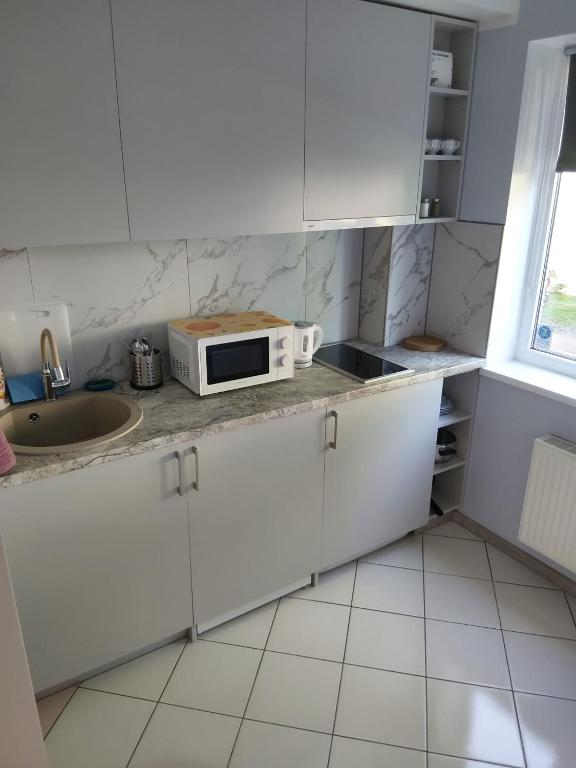 a kitchen with white cabinets and a microwave on a counter at Apartament orhideja 11 in Riga