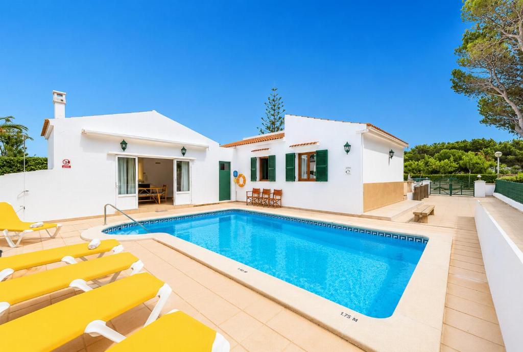 a villa with a swimming pool and yellow chairs at Villa Estrella in Cala en Blanes
