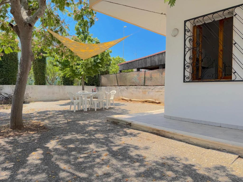 a patio with a table and chairs and a tree at Villetta Chiara in Baia Verde