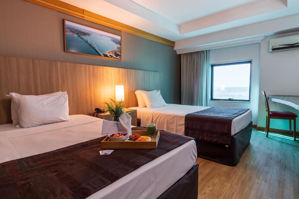 a hotel room with two beds and a tray of food at Planalto Bittar Hotel e Eventos in Brasília
