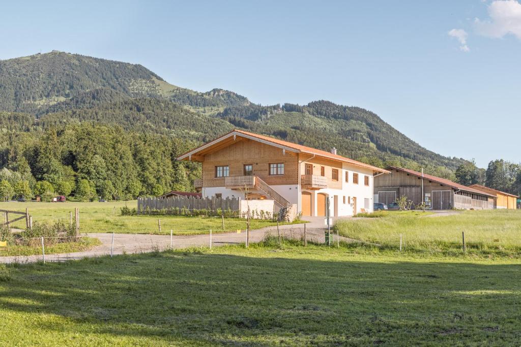 a house in a field with mountains in the background at Alpen Lodge Samerberg in Samerberg