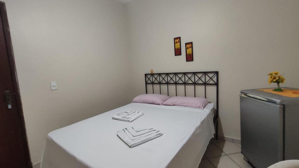 a small bedroom with a bed and a refrigerator at Pousada Requinte in Vila Velha
