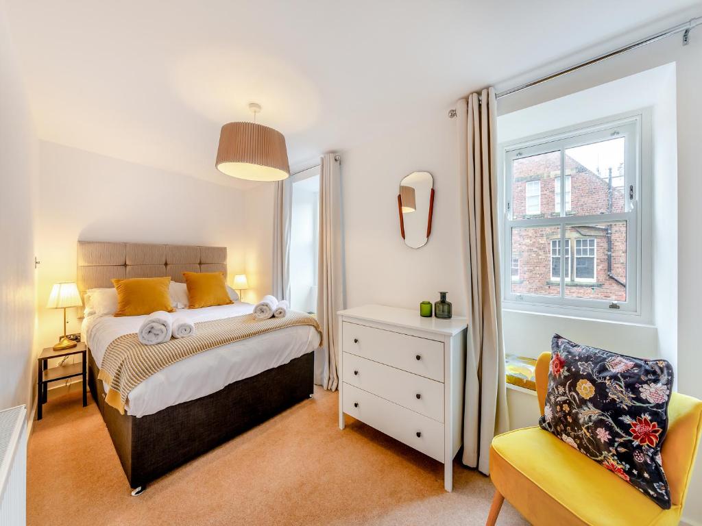 a bedroom with a bed and a chair and a window at Town Square House - Uk45610 in Alnwick