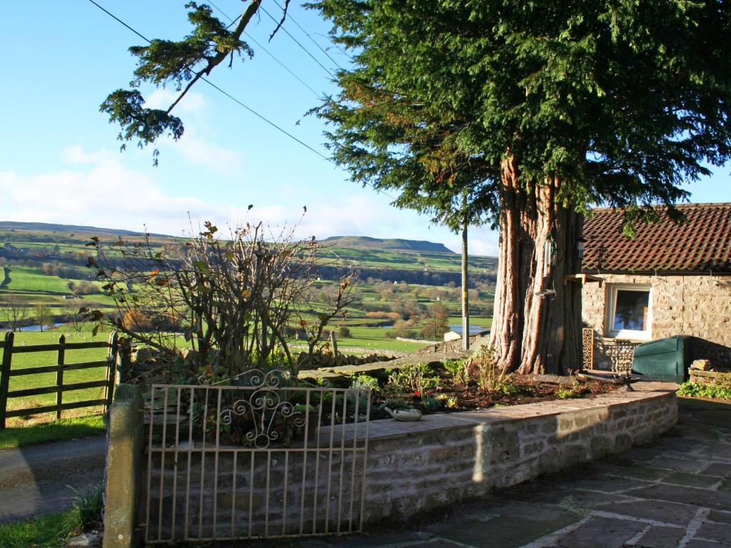 a house with a tree and a fence at Bloomer's Bothy in Askrigg