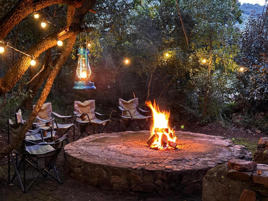 a fire pit in a yard with chairs and lights at Ntsinini Trout & Leisure Farm in Waterval Boven