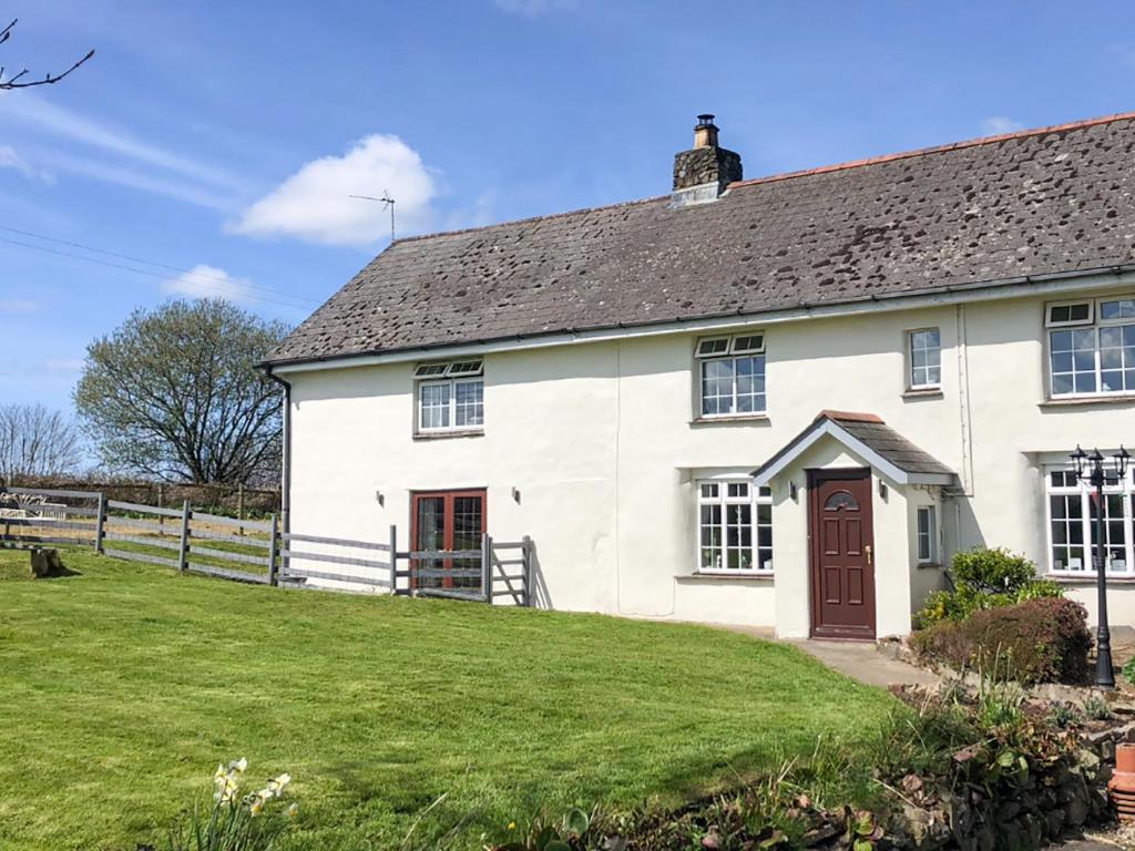 an old white house with a grassy yard at Holemoor Cottage in Bridgerule
