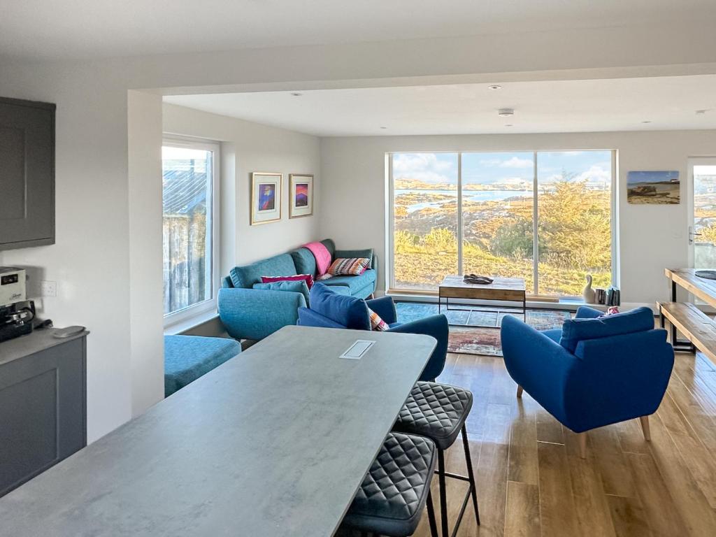 a living room with a table and blue chairs at Grianan in Eriskay