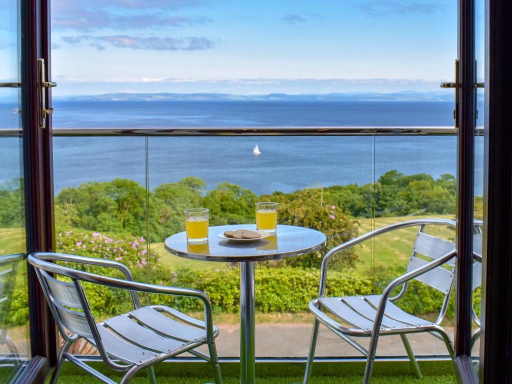 a table with two chairs and two glasses of orange juice at Woodlea Cottage 1 in Dippin