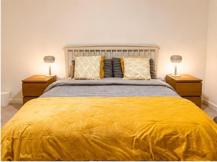 a bedroom with a large yellow bed with two lamps at Stunning 1 Bed Luxury Apartment in Erith