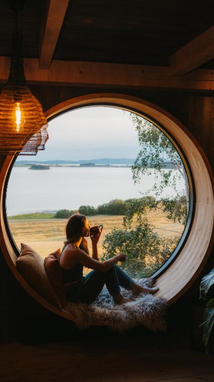 a woman sitting in a round window taking a picture at Fuglekassehytta in Sparbu