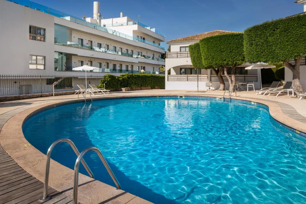 una grande piscina blu di fronte a un edificio di Alcanada Golf Hotel a Port d'Alcudia